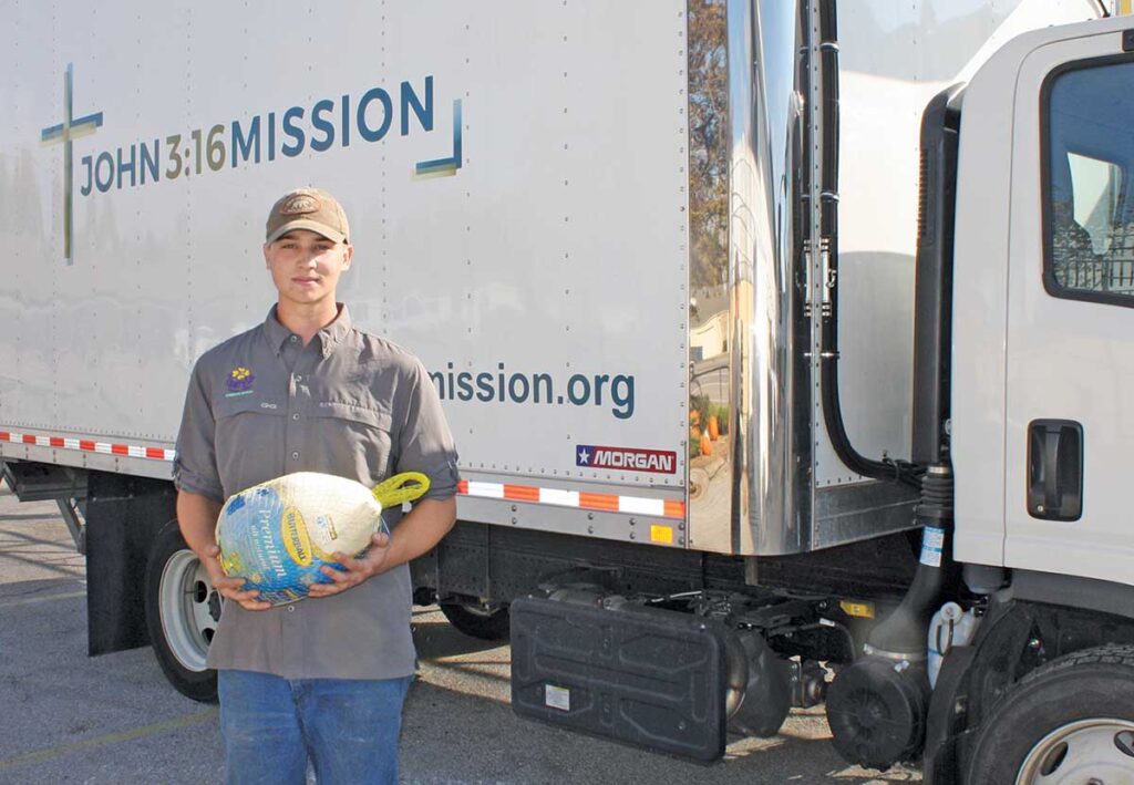 Jake Bay holds a frozen turkey donated to help John 3:15 Mission