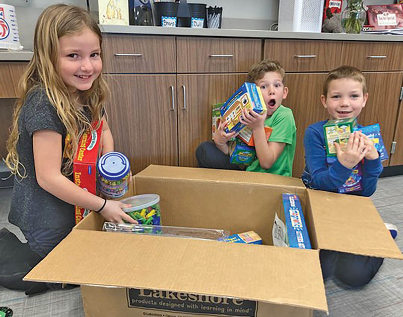 First-grade students Caroline Roberts, Crosby Ross and Kellan Hodges unpack new learning activities bought with a Grant awarded to teacher Stefanie Soucek at Morrow Elementary School, Owasso Public Schools. The children said it felt like Christmas.